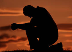 muž se modlí na jednom koleni